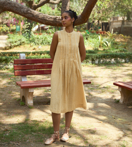 Sleeveless gingham kala cotton midi dress with pleated yoke and hidden brass buttons, handcrafted from organic cotton.