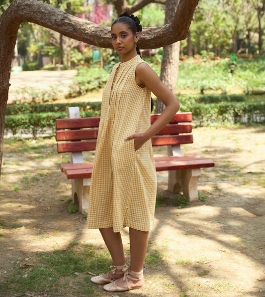 Sleeveless gingham kala cotton midi dress with pleated yoke and hidden brass buttons, handcrafted from organic cotton.