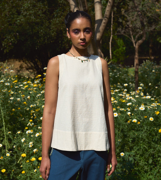 Sleeveless khadi cotton trapeze top with a brass button closure, lightweight and breathable.