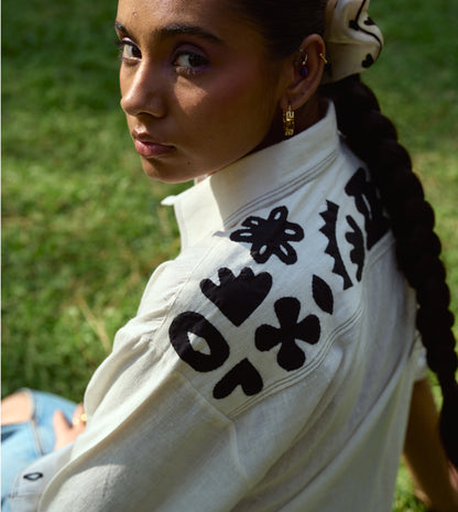 Full-sleeve kala cotton shirt with hand-stitched appliqué patterns and corozo buttons, relaxed fit.