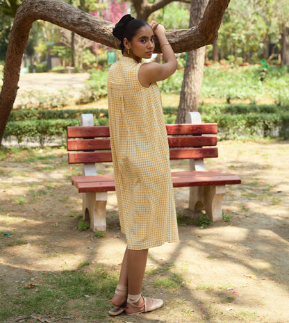 Sleeveless gingham kala cotton midi dress with pleated yoke and hidden brass buttons, handcrafted from organic cotton.