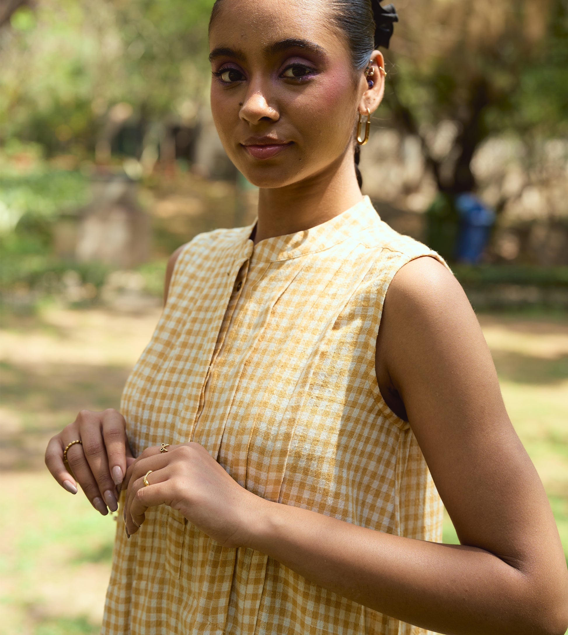 Sleeveless gingham kala cotton midi dress with pleated yoke and hidden brass buttons, handcrafted from organic cotton.